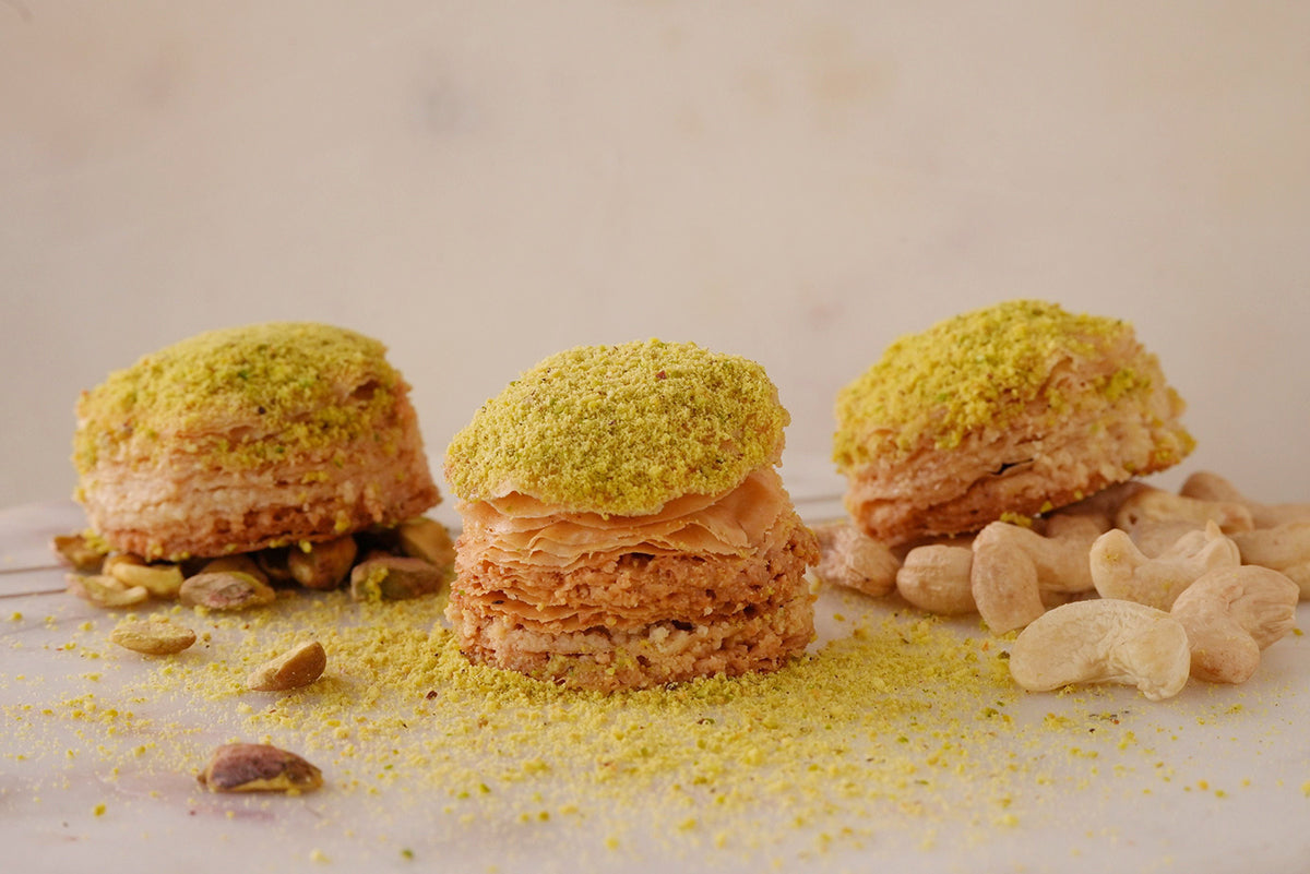 3 pieces of traditional Sogarina baklava, dusted with pistachio and showing the multiple layers of flaky pastry and cashew nuts.