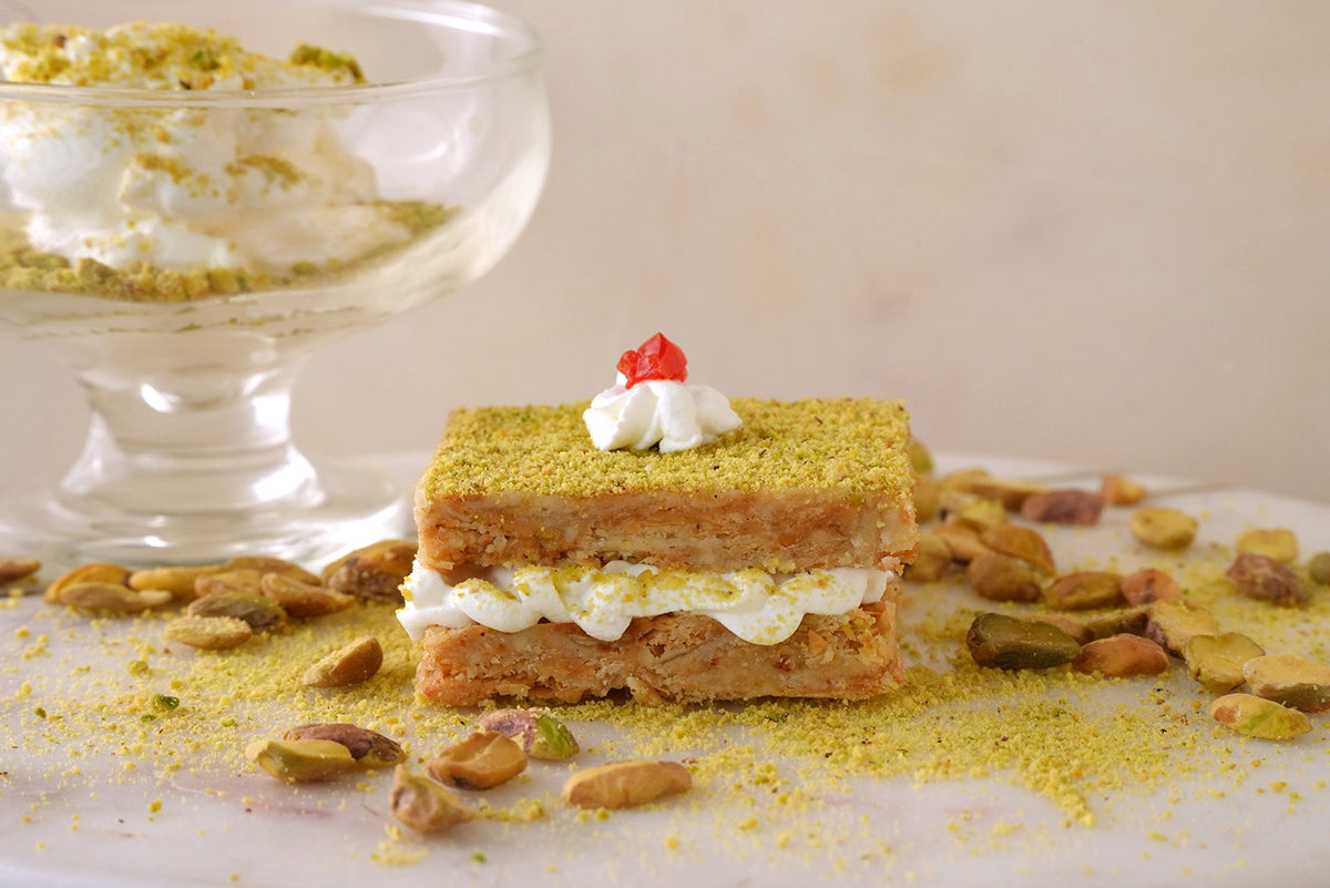Image of Sogarina Strati, our baklava ice cream sandwich, on a white counter that is decorated with whole pistachios.